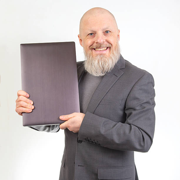 istock Smiling man in a suit presenting a sleek object against a plain background 2233115416