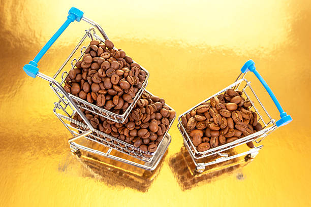 istock Coffee beans overflowing from mini shopping carts on a golden background 2233116171