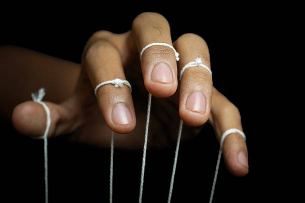istock male puppeteer hand with strings isolated on black background. manipulation or controlling concept 2233117548