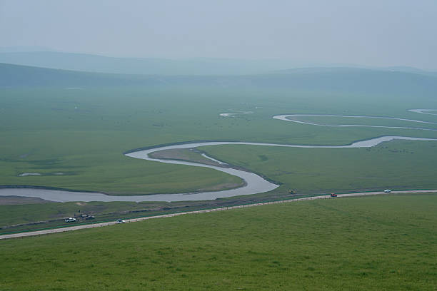 Serpentine River Meandering Through Expansive Grassy Plains Under Hazy Sky
