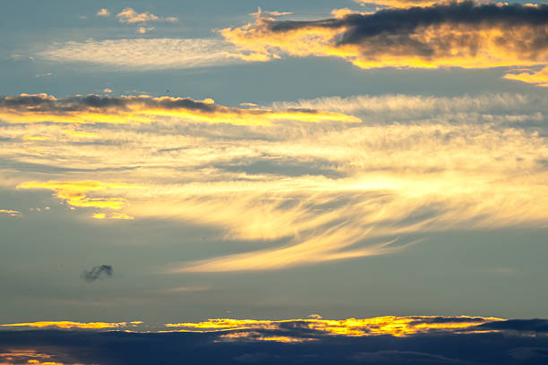 A breathtaking sunset unfolds with vivid colors painting the sky. Wispy clouds stretch across, reflecting shades of orange and yellow as daylight transitions into evening.