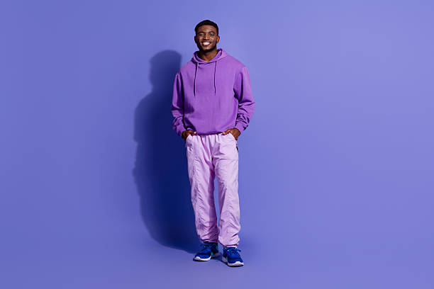 istock Young man in casual purple hoodie on solid background, confidently standing with hands in pockets, expressing positivity 2233122071