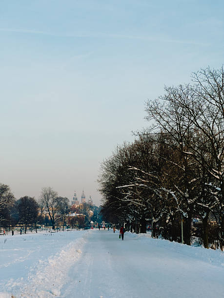 Snow covered path winding toward Wawel Cathedral in Krakow, Poland, features leafless trees blanketed in snow, with people strolling along, enjoying serene winter landscape. Snow, snow path, Cathedral
