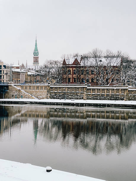 Panoramic view of Krakow reflecting on Vistula river during snowy winter day, featuring characteristic tower of St. Joseph's Church. Snowy panorama capturing historic Krakow cityscape, Vistula river