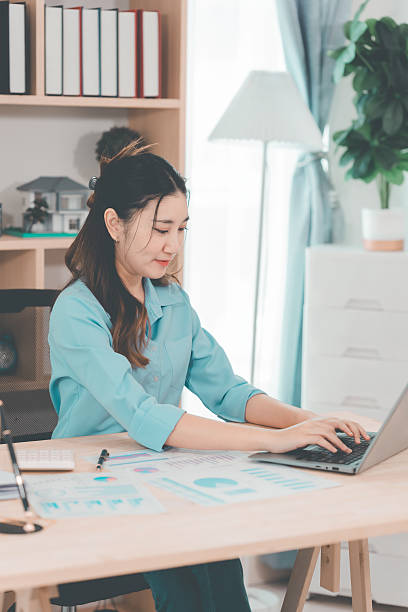 istock Young Asian woman accountant analyzing documents in office sitting at table reading documents Analyze graphs working on company projects. 2233130200
