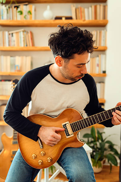istock Young man practicing and playing electric guitar at home 2233131027