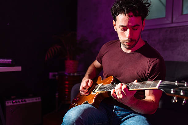 istock Man playing electric guitar at home music studio 2233131134