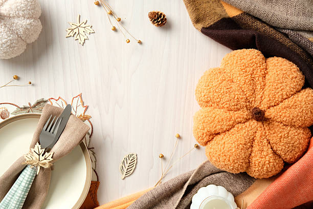 istock Autumn table setting with plush pumpkin, warm fabrics, plate with napkin and wooden leaf ring. Cozy seasonal decor for Thanksgiving, fall celebration, and rustic home ambiance. 2233131354