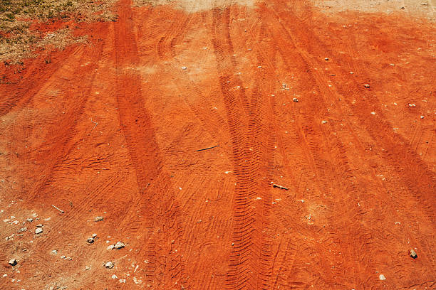Tire tread marks on dry red soil road. High angle view.