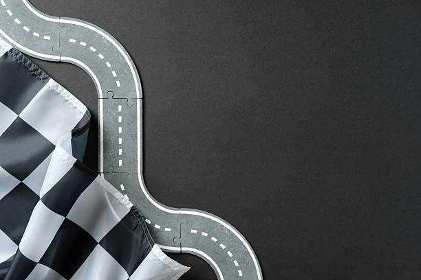 istock Curved puzzle road with dashed lines and checkered flag on dark background. Racing concept. 2233131600