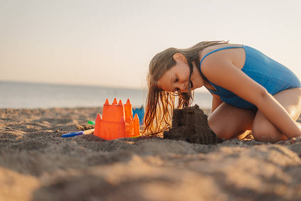 istock Girl building sandcastle on beach at sunset 2233132339