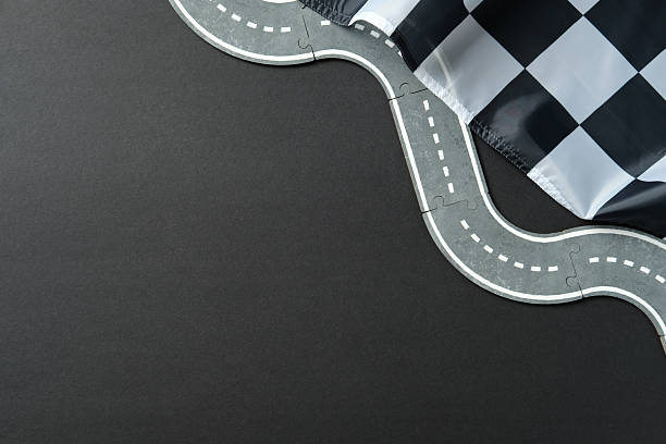 istock Winding puzzle road with dashed lines and checkered flag on dark background 2233132345