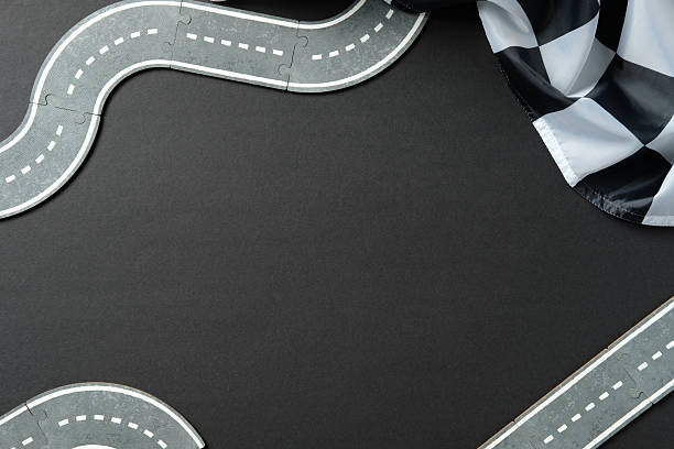 istock Winding toy road on black background with checkered flag. 2233132353