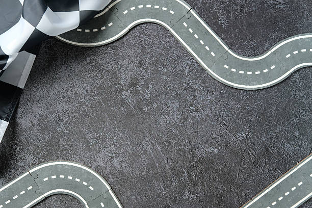 istock Winding toy road on textured asphalt with checkered flag. 2233132364