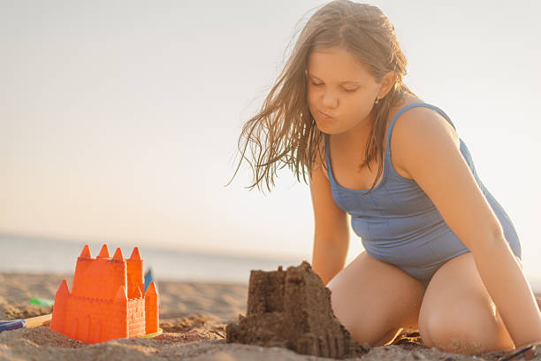 istock Girl building sandcastle on beach at sunset 2233132413