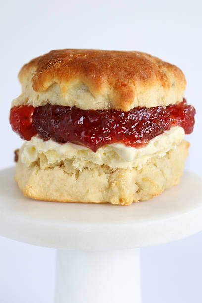 istock Image of white afternoon cream tea, plain and fruit scones, sliced with clotted cream, strawberry jam, accompanied by cake, biscuit 2233137315