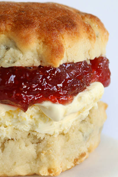 istock Image of white afternoon cream tea with plain and fruit scones, sliced and served with clotted cream and strawberry jam 2233138235