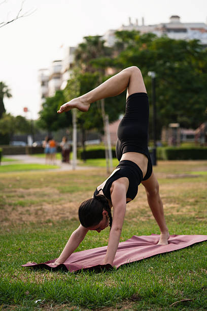 istock Young woman practicing yoga one-legged inverted pose in city park 2233139224