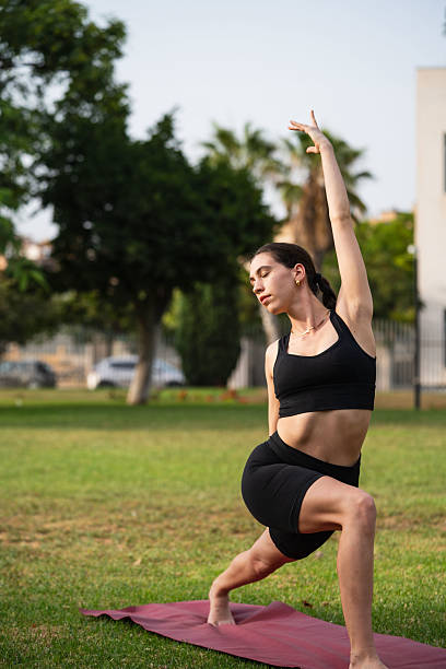 istock Young woman practicing yoga crescent lunge pose in park 2233139226