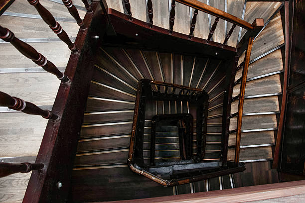 An amazing downward view capturing the geometric symmetry and sharp depth of the dark wooden steps and central square well.