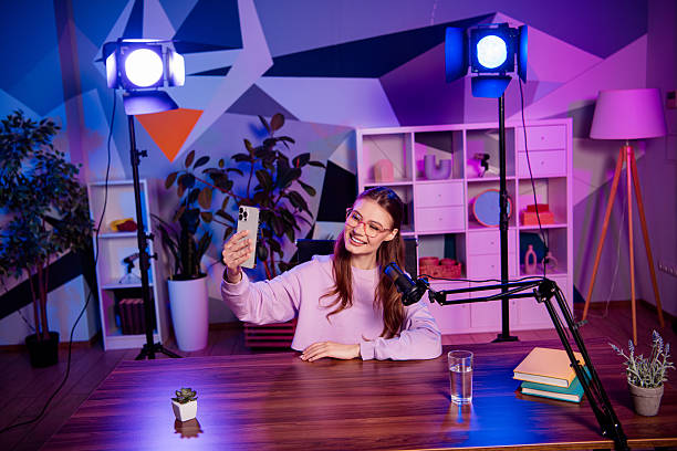 istock Popular blogger hosting a podcast with engaging visuals in a colorful studio featuring modern microphone equipment and neon lighting. 2233143016