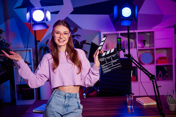 istock Popular female vlogger in a vibrant indoor studio holding a clapperboard with modern equipment reflecting casual professionalism 2233143313