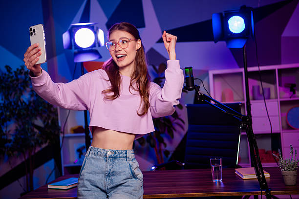 istock Young female vlogger taking a selfie while recording in a modern neon-lit studio 2233143316