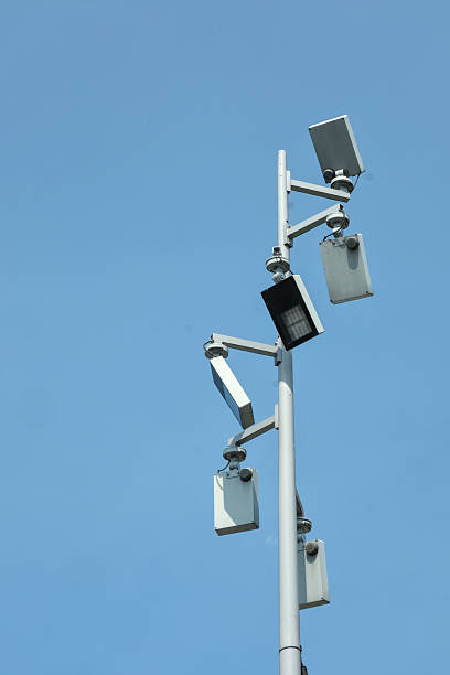 istock Tall pole with multiple surveillance cameras and LED light against a clear blue sky, designed for wide area security monitoring. 2233143375