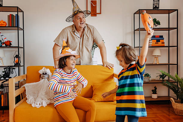istock Father decorating living room for Halloween with his daughters 2233146185