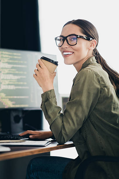 istock Charming female programmer working at her desk with a cup of coffee in hand in a modern workspace 2233146367
