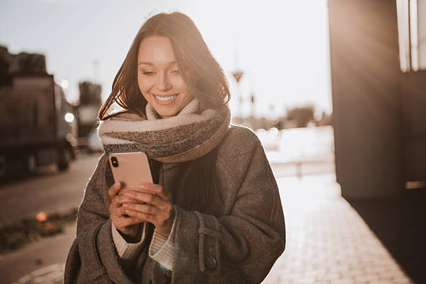 istock Chic young woman enjoys a sunny autumn day outdoors while using her phone 2233146962