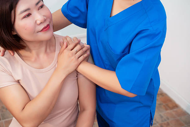 Close-up on a nurse consoling a patient and holding her hands at the hospital - healthcare and medicine concepts