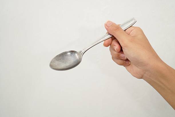 istock Female Hand Holding Stainless Spoon Isolated On White Background. Close up 2233152012
