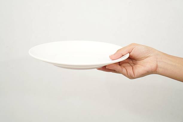 istock Woman's hand holding an empty plate isolated on white background 2233152048