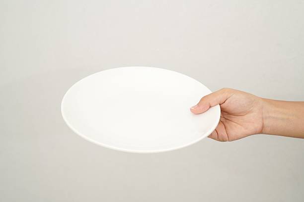 istock Woman's hand holding an empty plate isolated on white background 2233152050