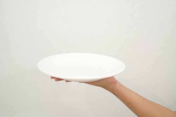 istock Woman's hand holding an empty plate isolated on white background 2233152064