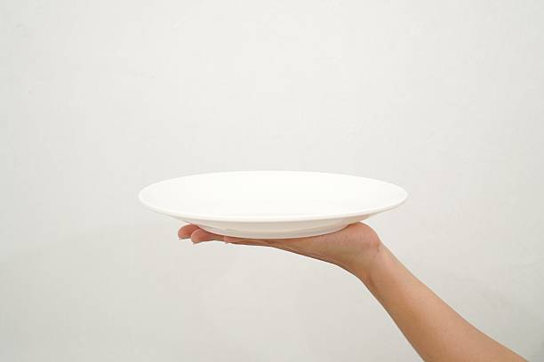 istock Woman's hand holding an empty plate isolated on white background 2233152065