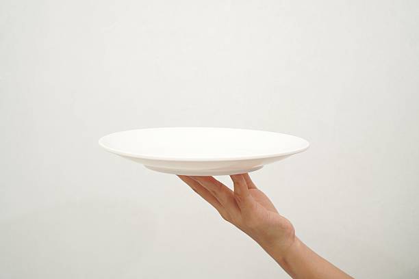 istock Woman's hand holding an empty plate isolated on white background 2233152067