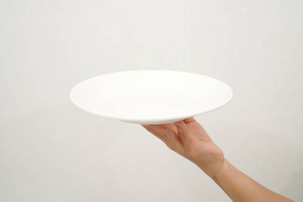 istock Woman's hand holding an empty plate isolated on white background 2233152068