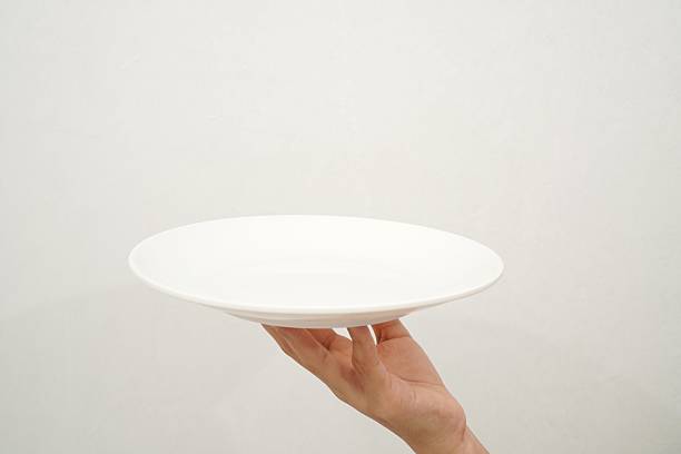 istock Woman's hand holding an empty plate isolated on white background 2233152075