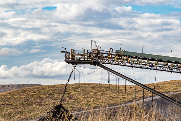 Coal mine scene featuring a conveyor system, large dump truck, and tailings stockpile. A powerful industrial landscape showcasing mining operations, heavy machinery, and resource extraction
