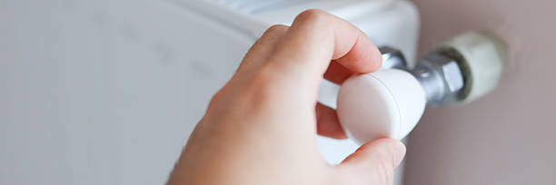 istock Adjusting radiator knob for optimal home heating efficiency close-up 2233159677