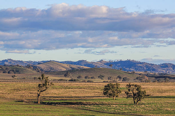 istock Scenic country landscape featuring rolling farmland, distant mountains, and a dramatic cloudy blue sky 2233160508