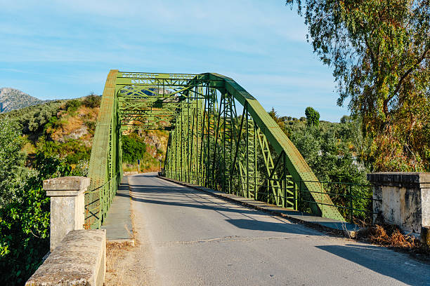from the center of the Luis de Arminan bridge, the road leads through olive-covered hills between Cuevas de San Marcos and Encinas Reales, crossing the Genil river in southern Spain