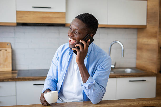istock Cozy morning – cheerful man with coffee chatting on phone in kitchen 2233161034