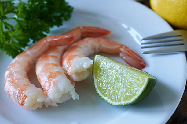 istock Boiled shrimp with lemon and parsley on a white plate. 2233162096