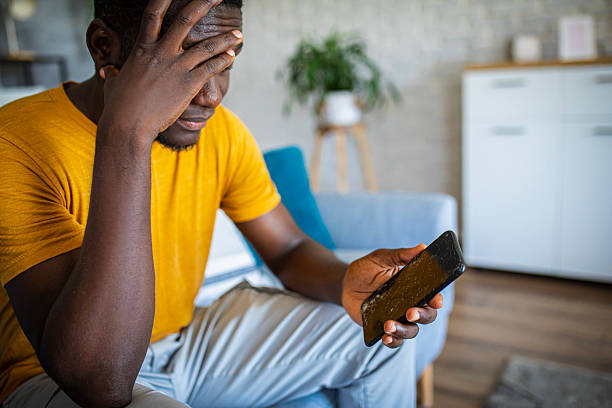 istock Young man holding cracked mobile phone screen, feeling upset and stressed 2233162792