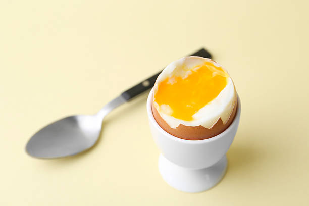istock Soft boiled egg in eggcup and spoon on beige background, closeup 2233162840