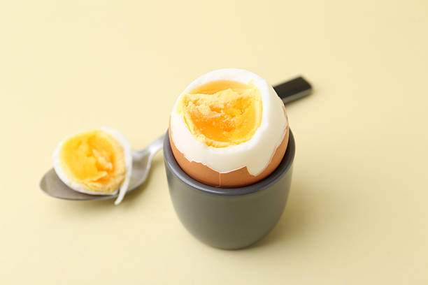 istock Soft boiled egg in eggcup and spoon on beige background, closeup 2233162902