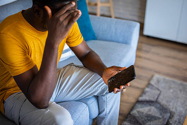 istock Young man holding cracked mobile phone screen, feeling upset and stressed 2233163273